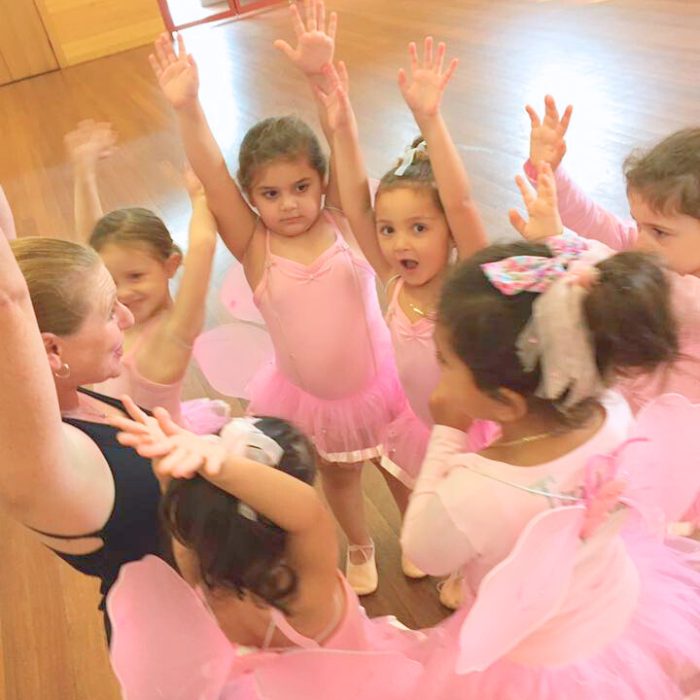 A group of children in pink tutus dancing with a teacher in a Tiny Tutus ballet class in Sydney.