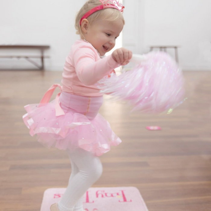 A young girl in a ballet tutu playing with pompom in a ballet class for 1 and 2 year olds.