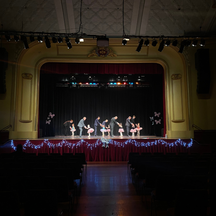Dads and their daughters dance on stage in an old theatre in Adelaide for the Tiny Tutus Recital Daddy Daughter Dance. 