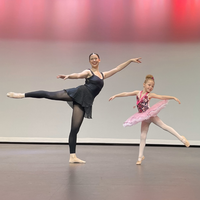 Teacher and ballerina posing on stage after a Tiny Tutus recital performance of ballet classes for 4 year olds.